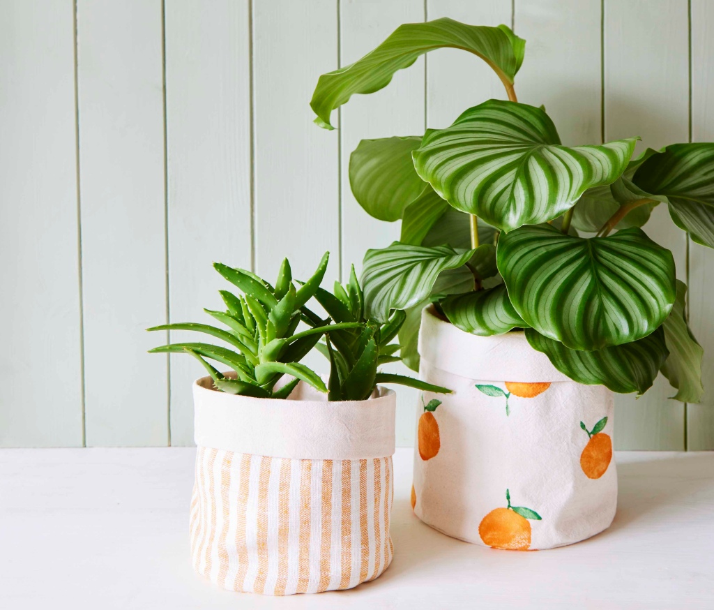 Two houseplants sitting in stitched fabric plant pot holders